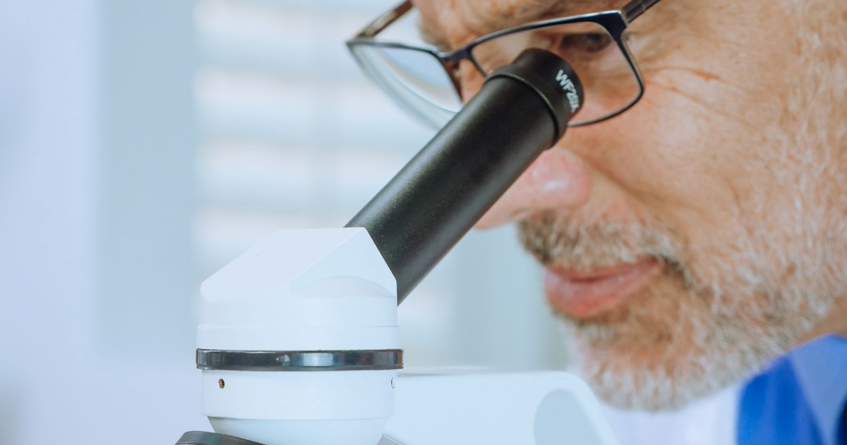 A researcher looks through a microscope in a laboratory.